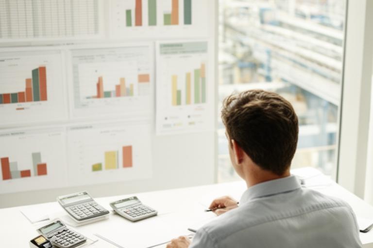 Planner comparing production capacity charts in a bright operations office